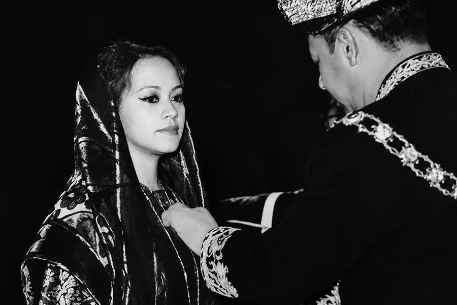 Black-and-white photograph of Saloma receiving an honour from a man in ceremonial Malay court dress