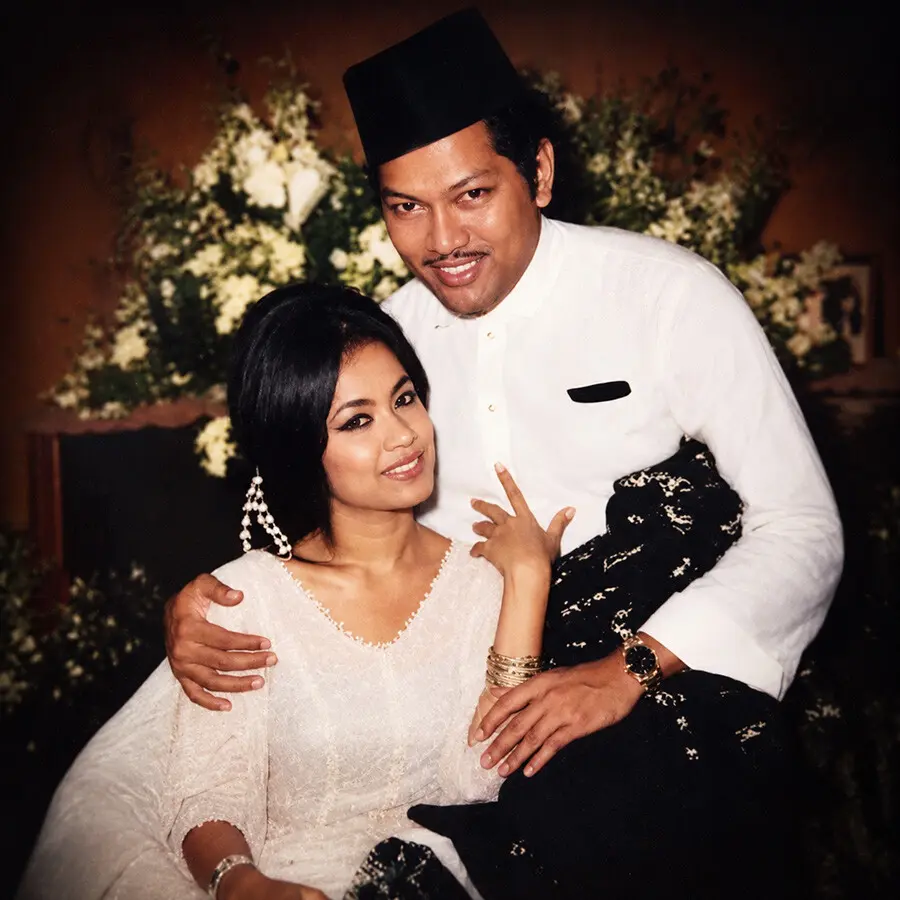 Colour portrait of Saloma and P. Ramlee together, seated, with a floral backdrop