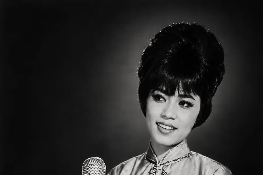 Black-and-white studio portrait of Saloma singing at a ribbon microphone